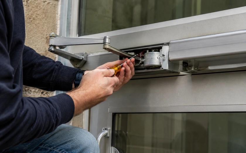 Technician repairing a commercial automatic door opener button at a business in Grand Junction, Colorado.