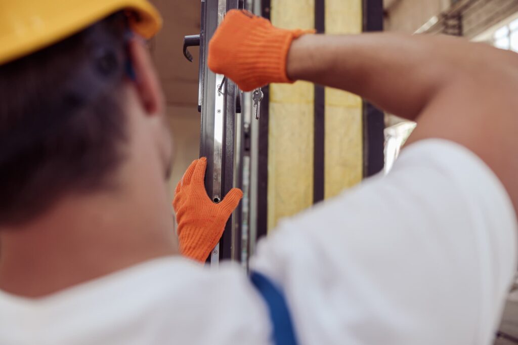 Technician repairing a commercial door dragging on the floor at a business in Glenwood Springs, Colorado.