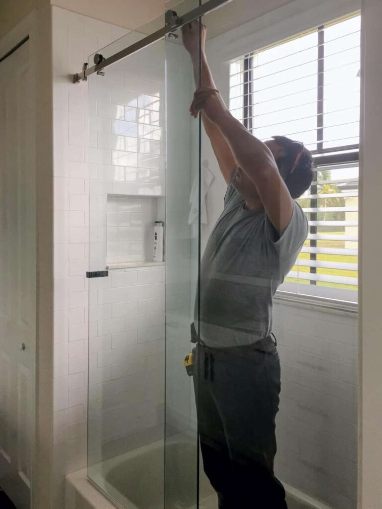 Technician adjusting a scraping glass shower door in a Grand Junction, Colorado bathroom.