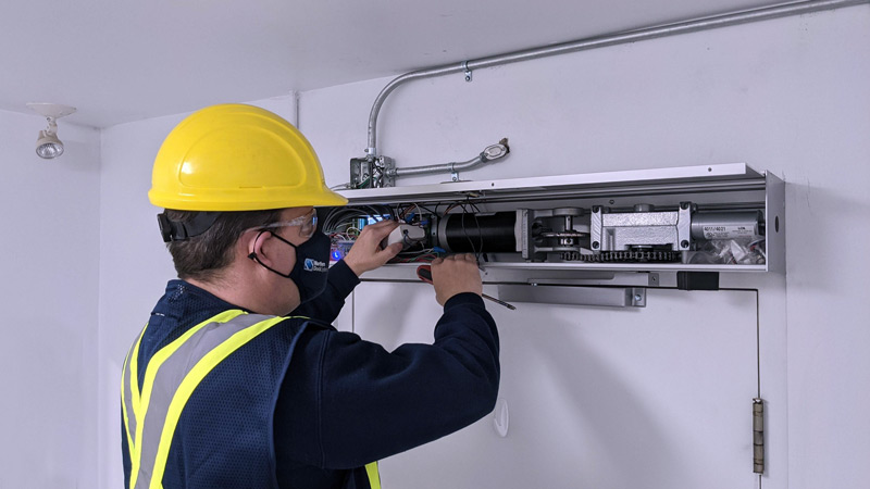 Technician inspecting an automatic commercial door opener at a business in Glenwood Springs, Colorado.
