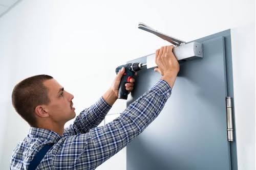 Technician adjusting a commercial door closer on a glass and aluminum door in Grand Junction, Colorado.